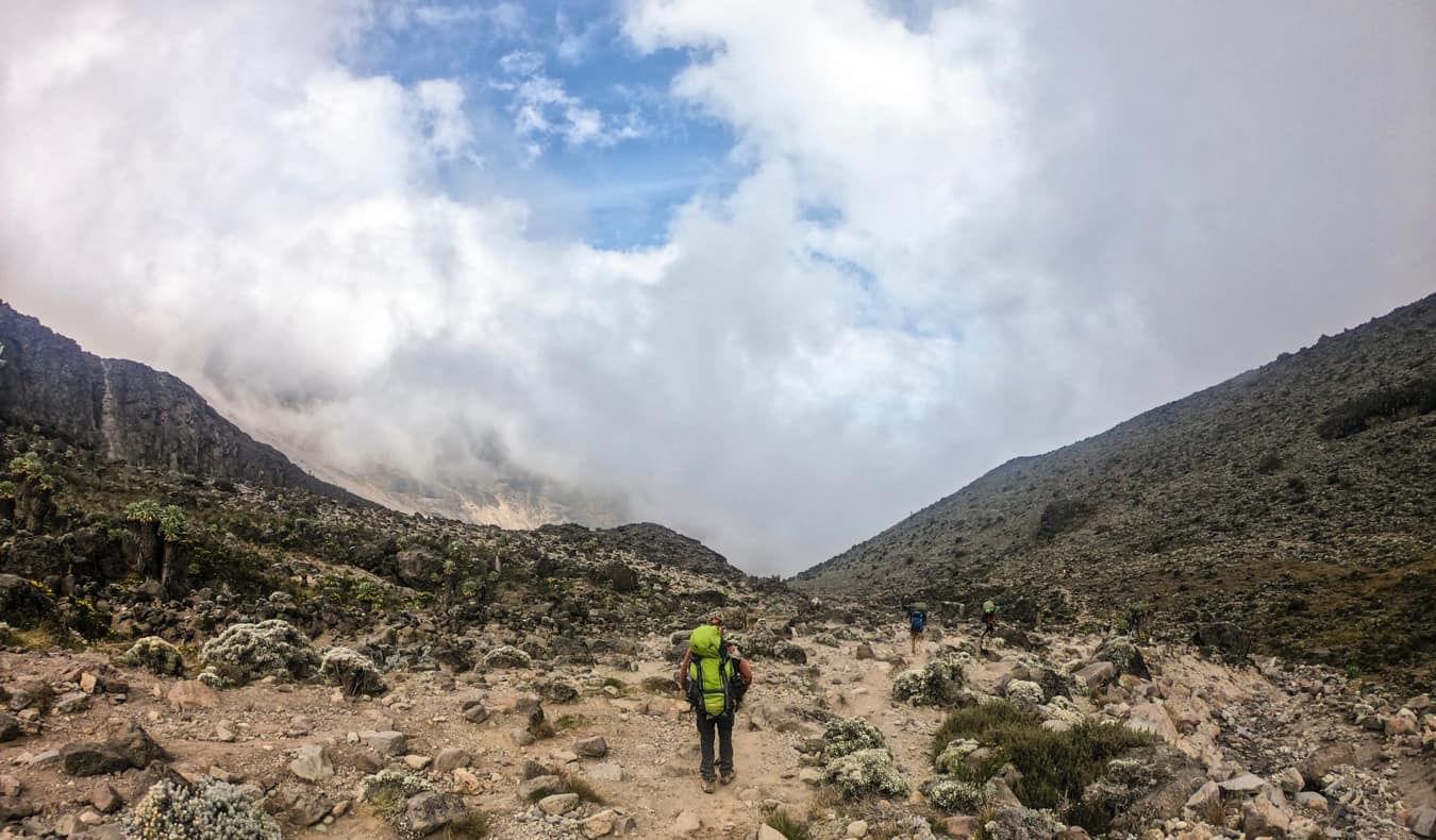 As pessoas caminham por uma das muitas rotas que sobem o Monte Kilimanjaro.
