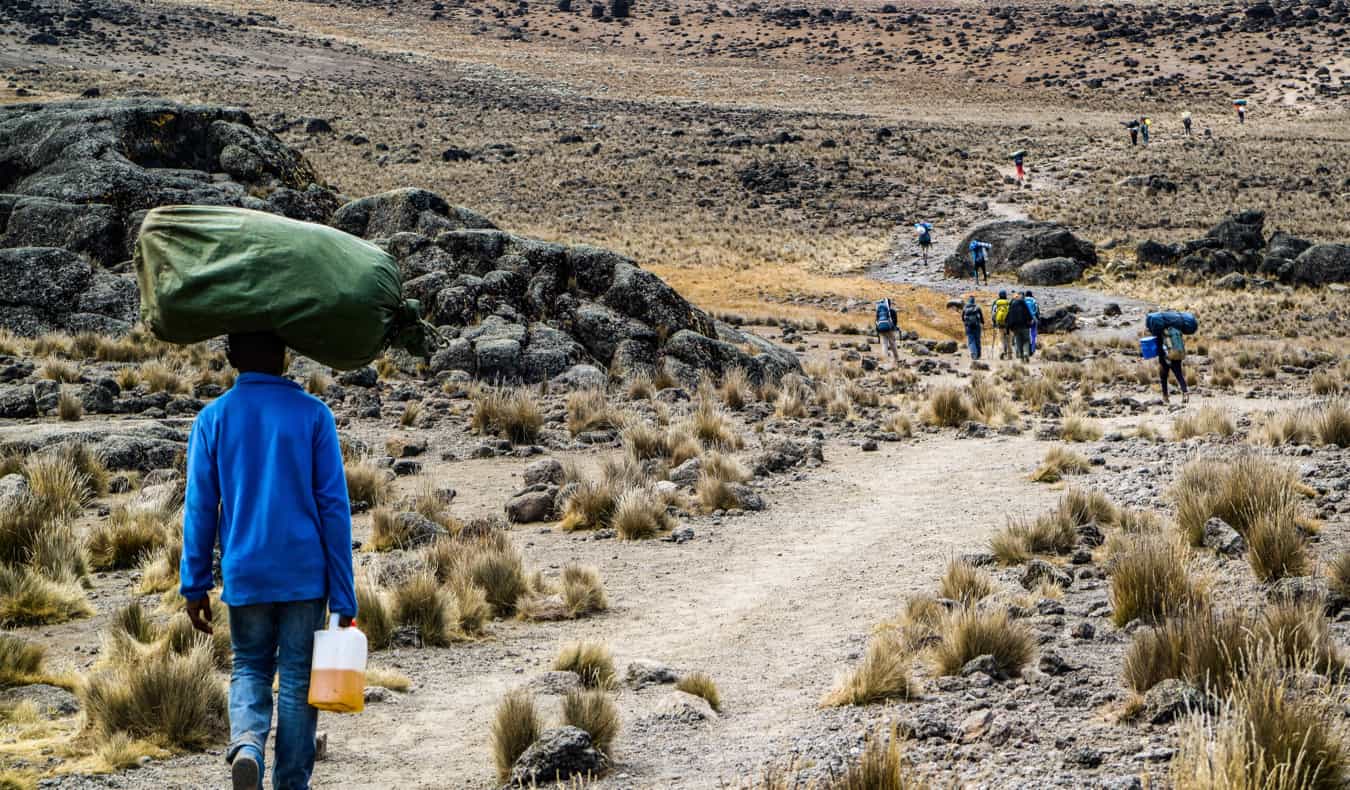 Porter no Kilimanjaro com um grande saco na cabeça