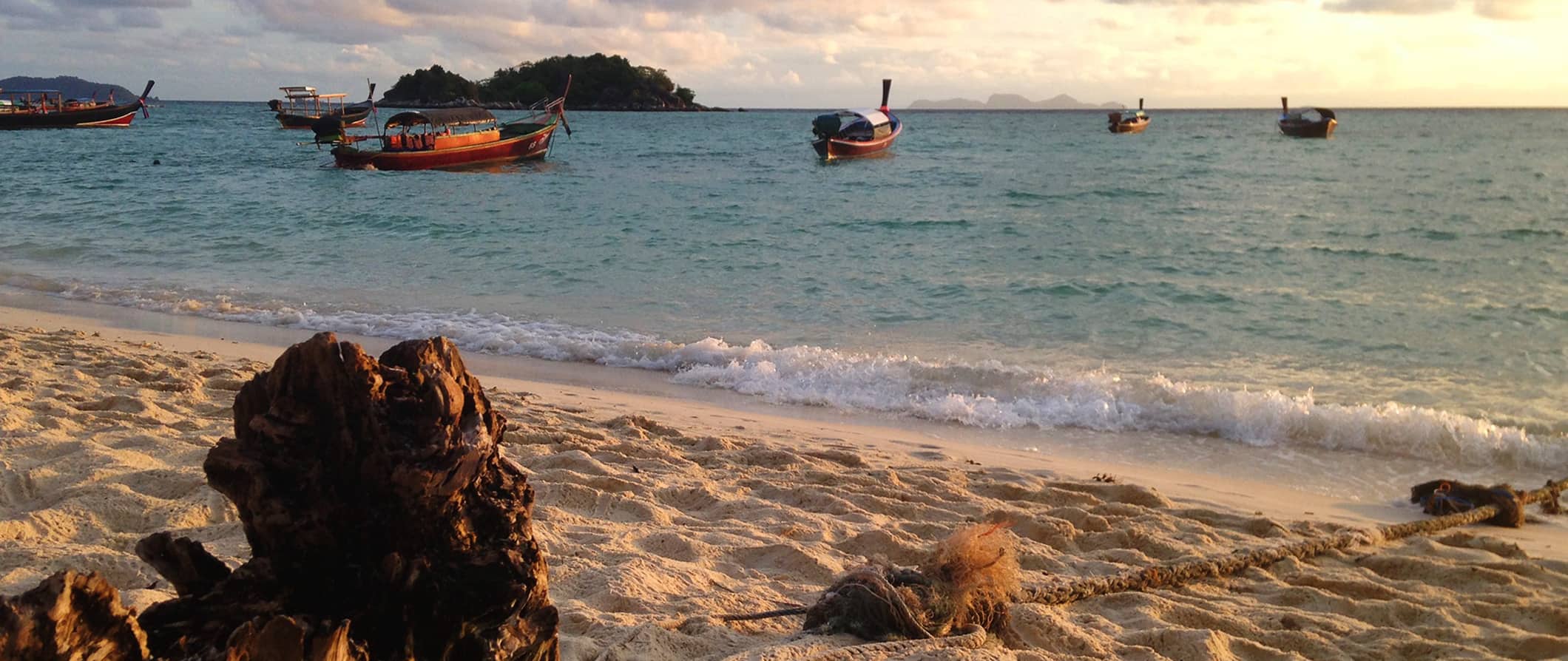 Uma praia vazia em um lábio, Tailândia, com pequenos barcos parados na costa