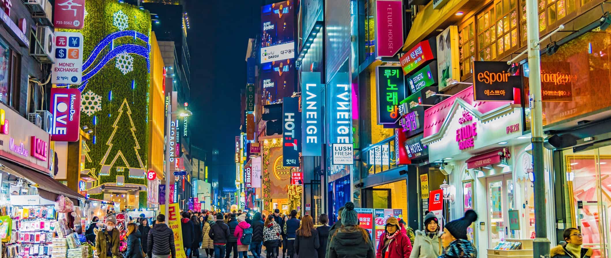 Morários e turistas em uma animada rua Seoul Street na Coréia à noite com muitos sinais brilhantes
