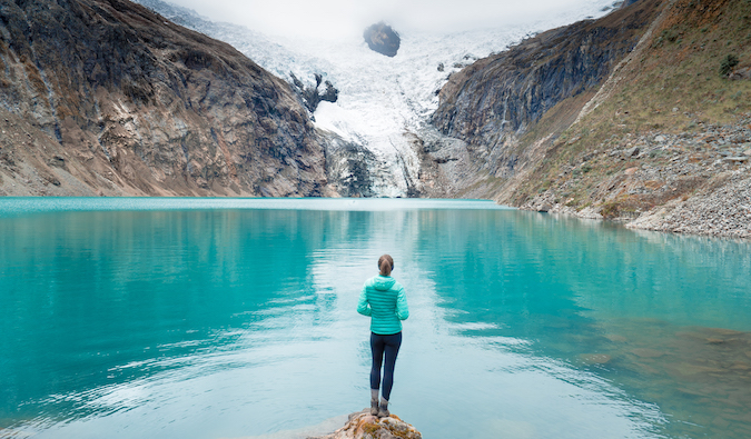 Christine Addis posa em frente a um lago azul brilhante nas montanhas