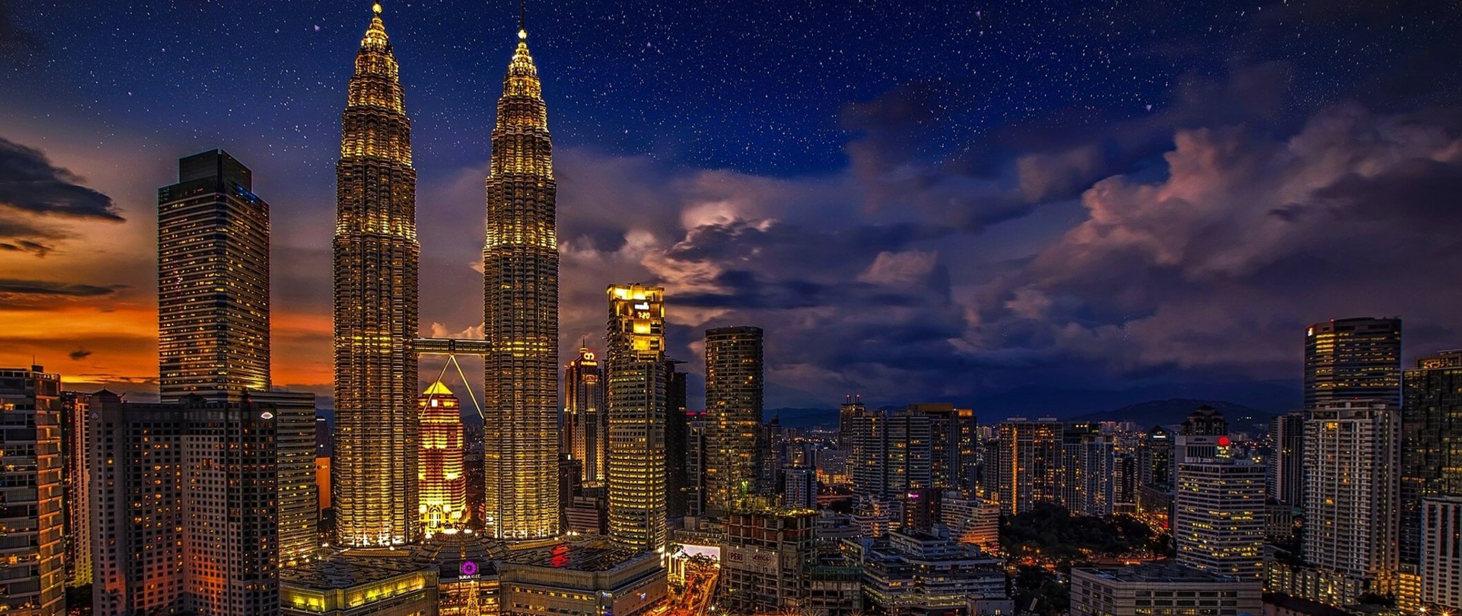 Uma linha impressionante do horizonte de Kuala Lumpur, iluminada à noite, com as torres de Petronas