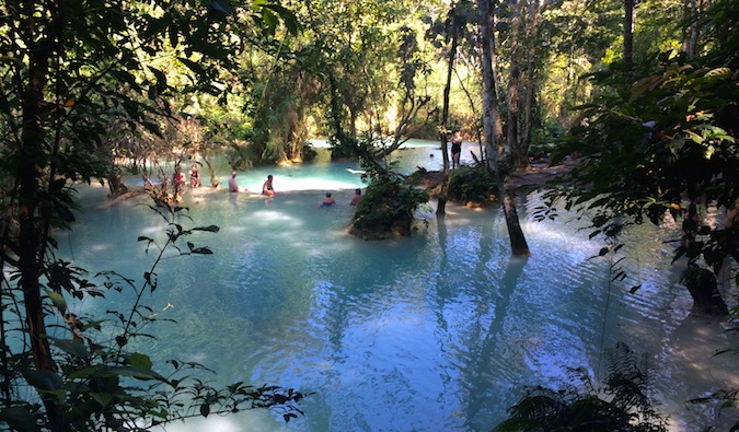 Viajantes nadam nas cachoeiras de Kuang Si, no Laos