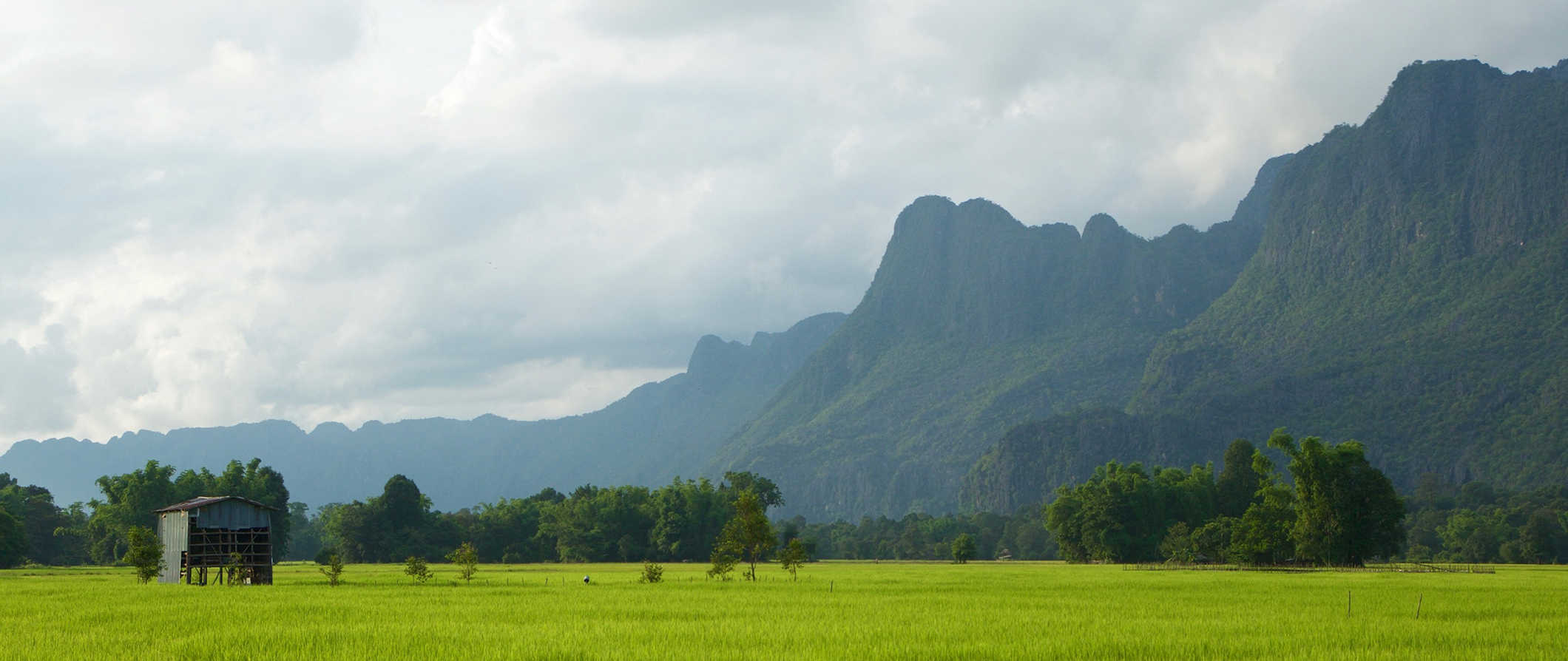 Hills Lush e montanhas de belo Laos com um campo verde em primeiro plano.