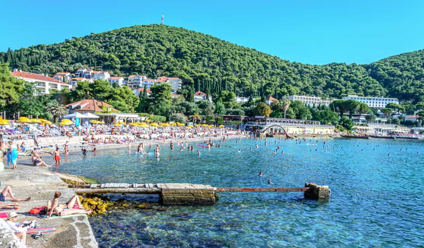 As pessoas relaxam na praia de Lapad em um dia ensolarado em Dubrovnik, Croácia