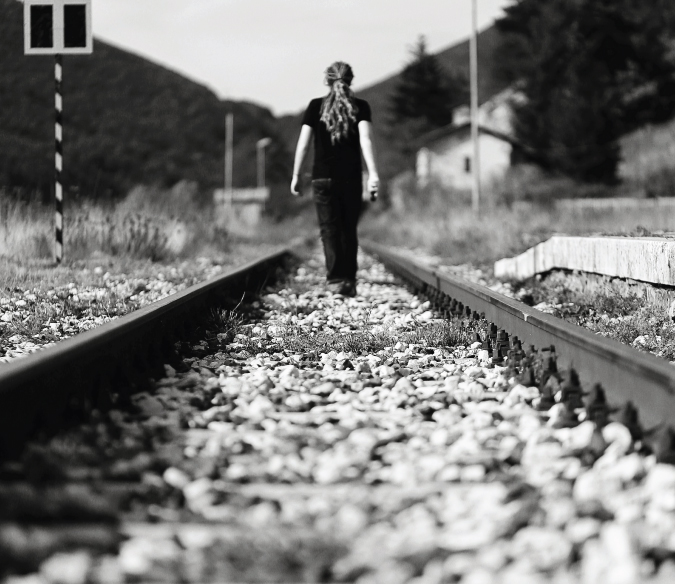 Auto-retrato preto e branco de Lawrence, caminhando ao longo dos trilhos da ferrovia