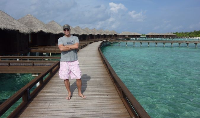 Lee Abbamonte fica em um longo píer de madeira nas Maldivas