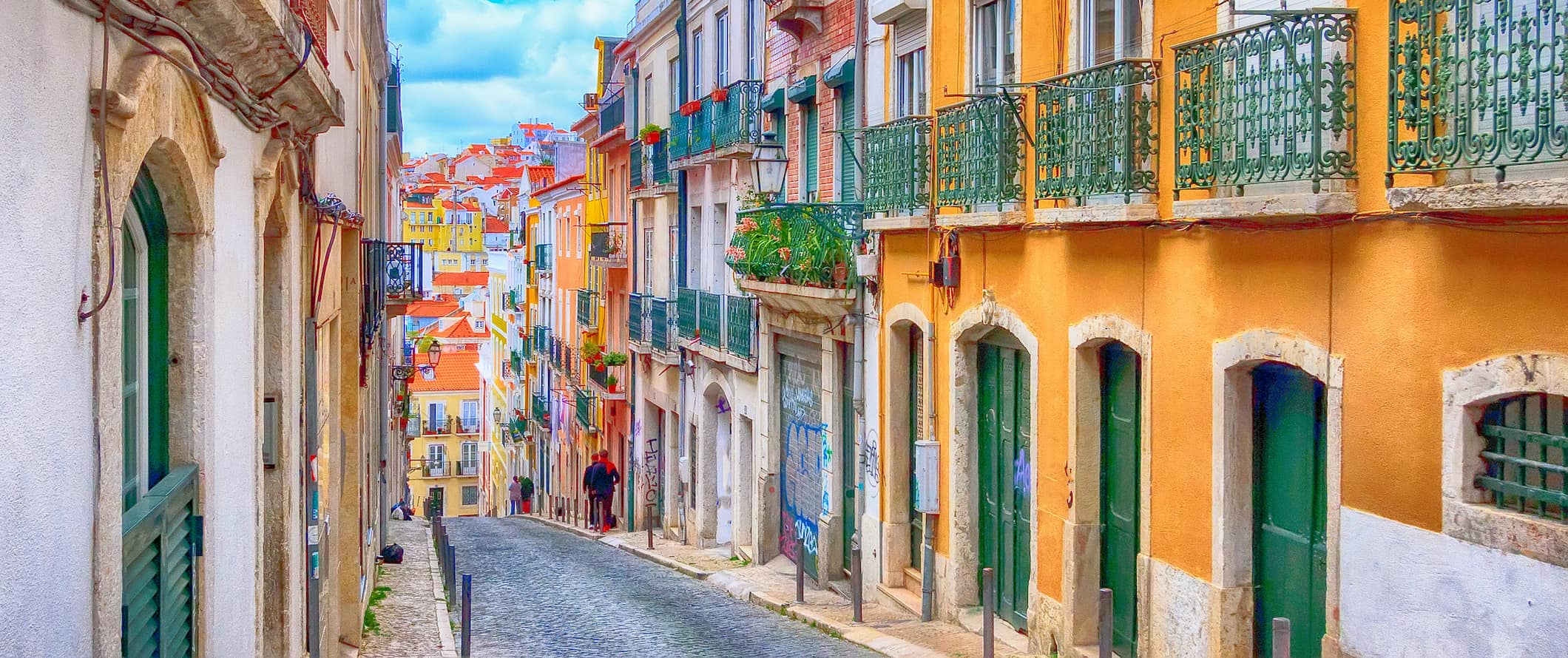 Os habitantes locais estão andando por uma rua estreita colorida em Lisboa, Portugal