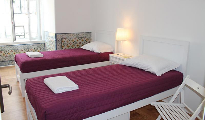 Duas camas de solteiro na sala branca do albergue Lost Inn Lisboa, Lisboa