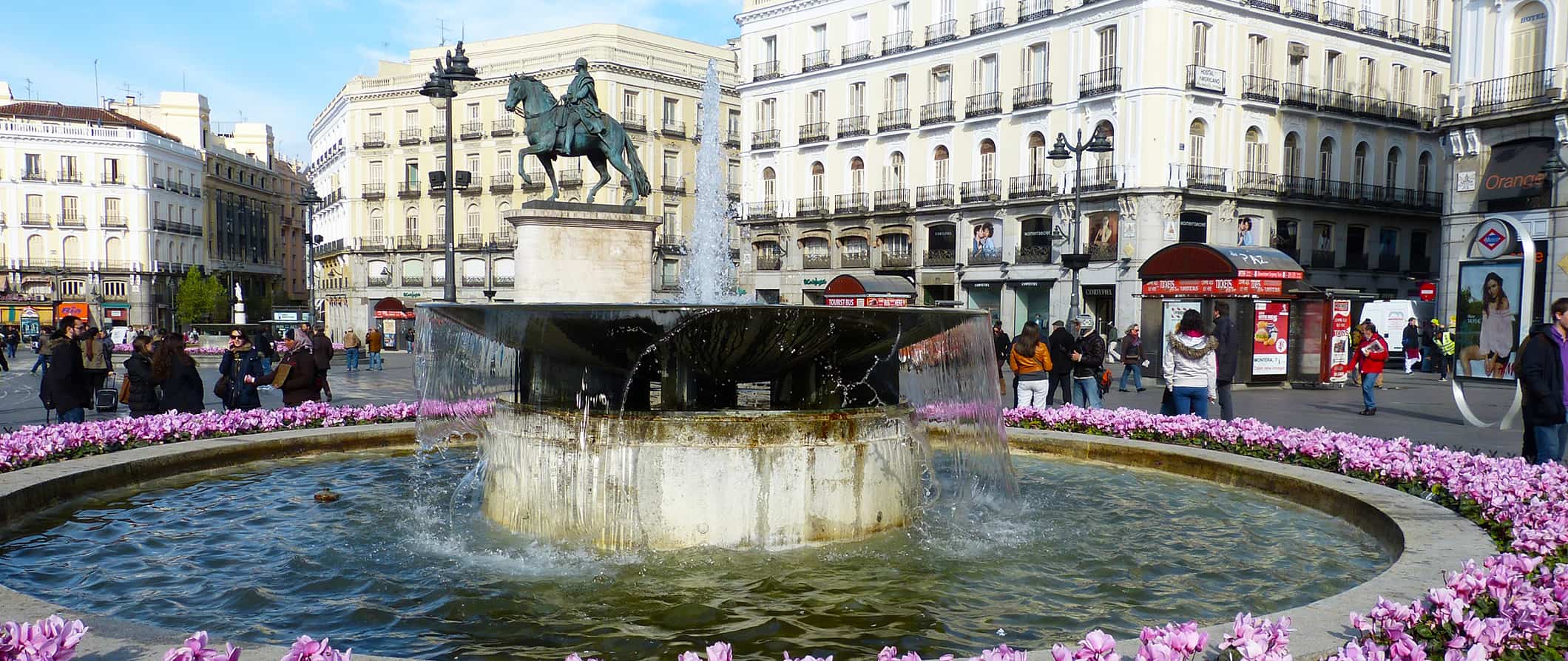 Pessoas se lotam em torno de uma enorme fonte histórica em um dia ensolarado em Madri, Espanha