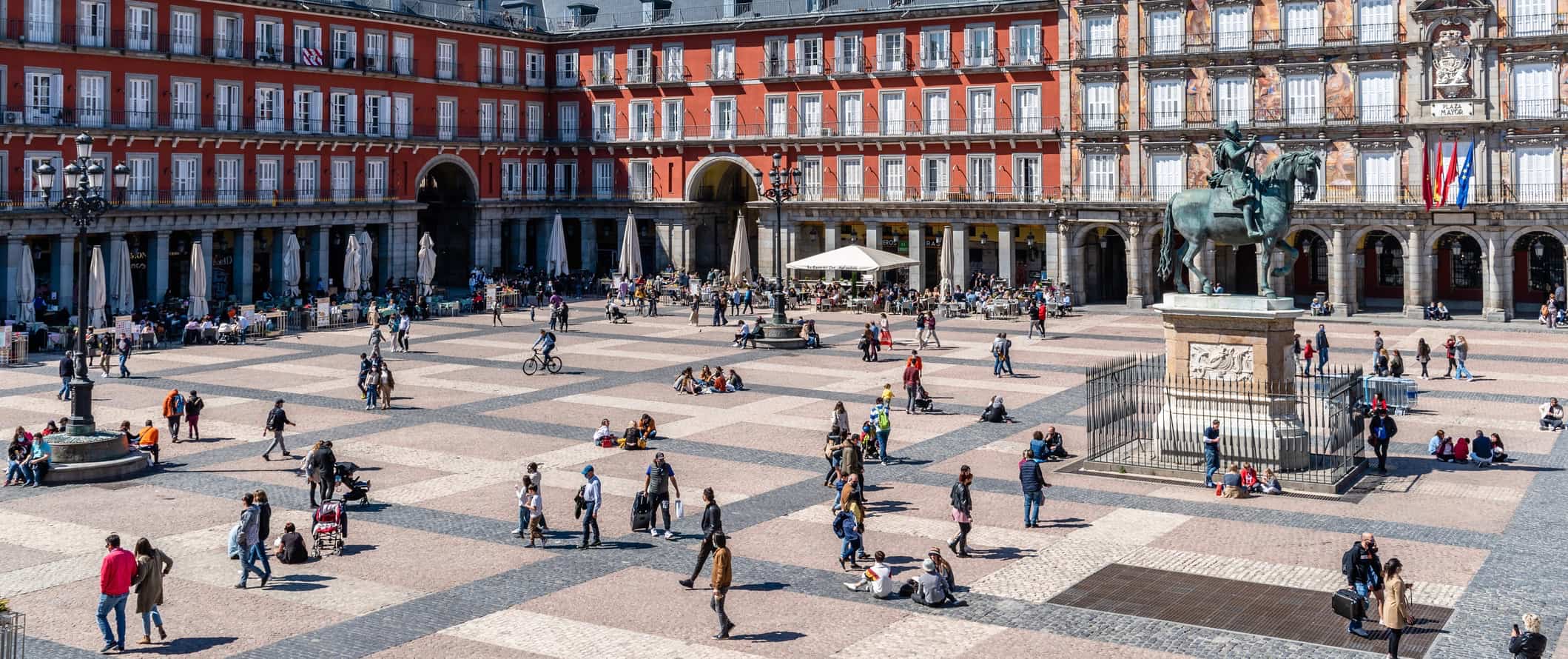 As pessoas descansam e andam em uma enorme praça em Madri, Espanha