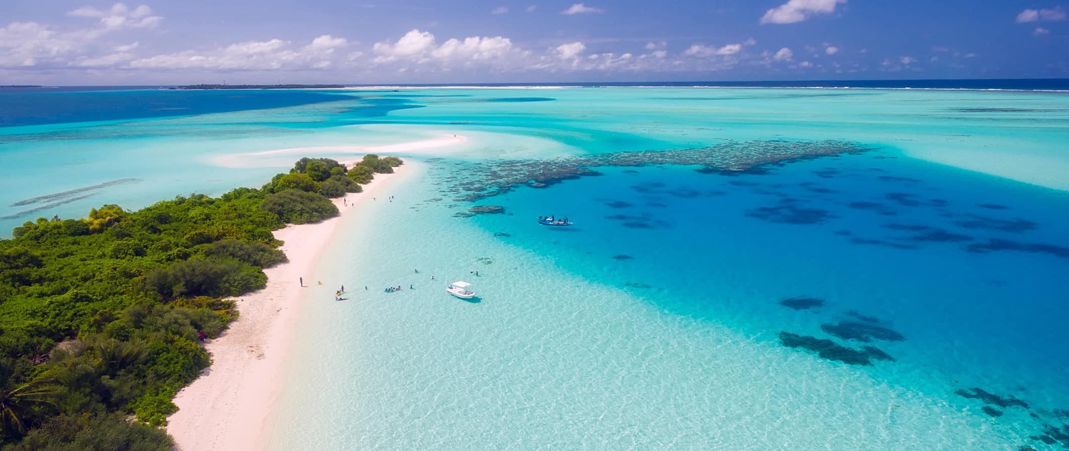 Águas transparentes deslumbrantes do mar tropical nas Maldivas ao longo de uma praia estreita com areia branca