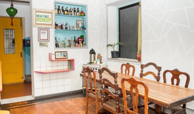 Cozinha rústica com mesa e cadeiras de madeira no Mambembe Hostel no Rio de Janeiro, Brasil