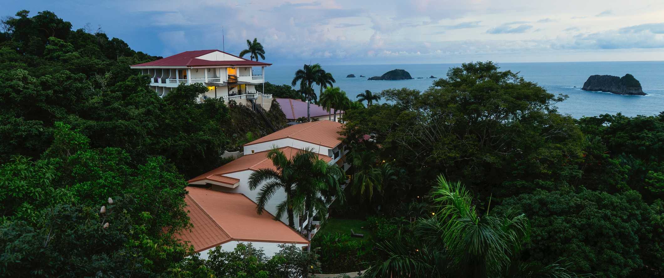 Pequenos edifícios do resort e hotel localizados na floresta tropical, com o oceano em segundo plano em Manuel Antonio, Costa Rica