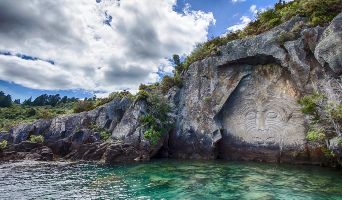 Fresco maori esculpido em uma pedra pela água na Nova Zelândia