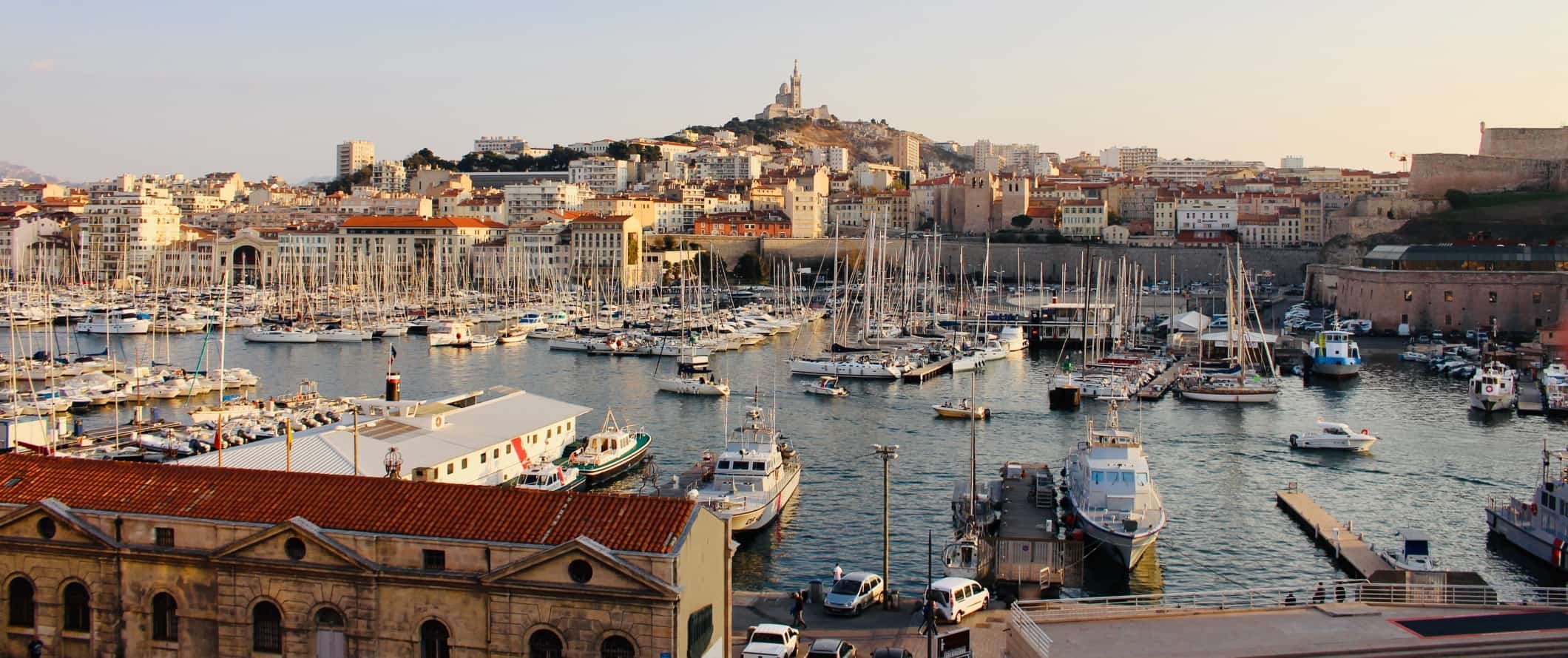 O porto antigo, cheio de veleiros, com a cidade de Marselha se elevando atrás dele na França