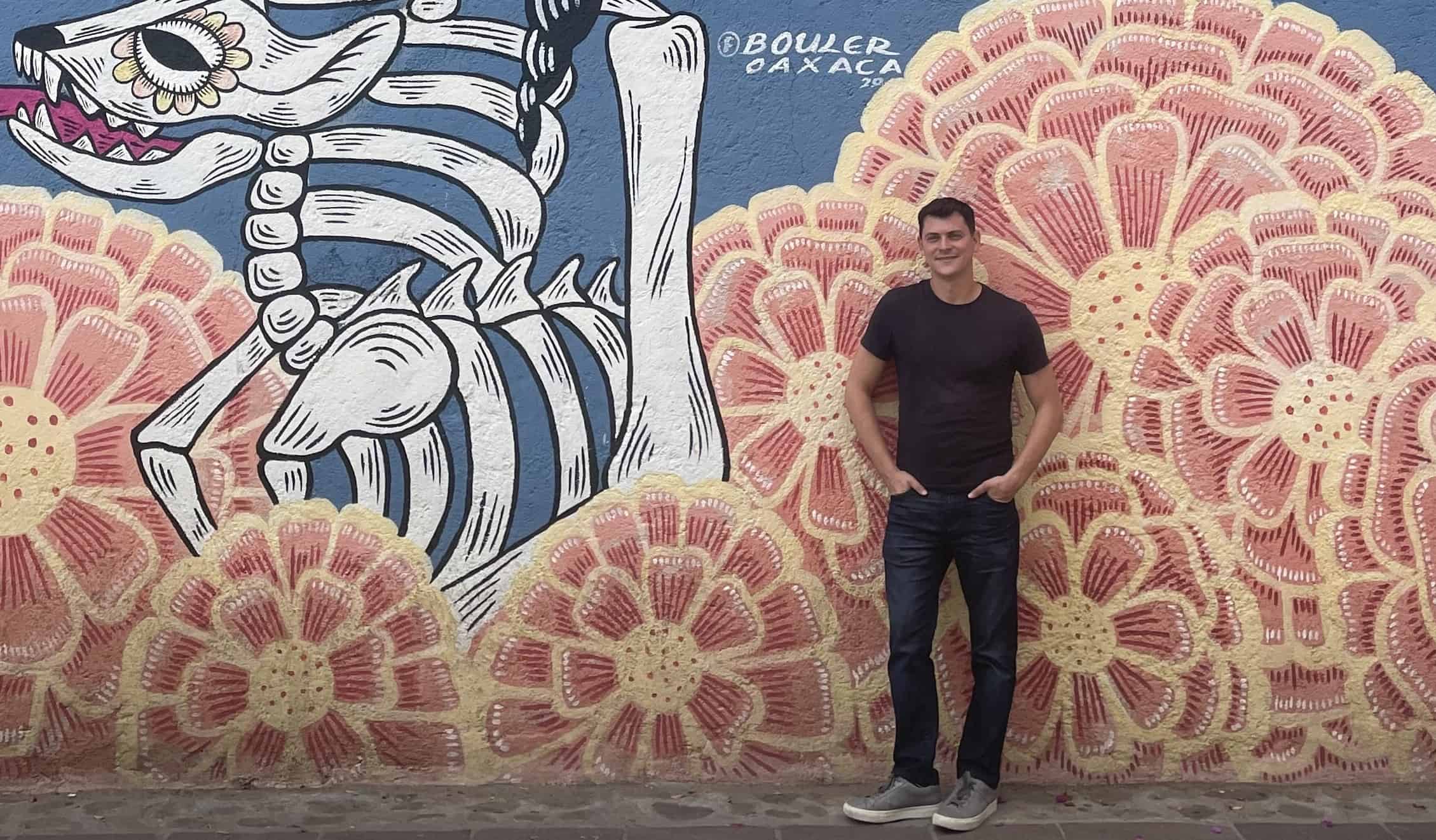 O Nomad Matt fica em frente ao esqueleto e arte da Flower Street em Ohak, México