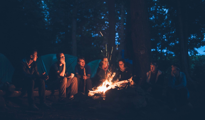 Um grupo de amigos e viajantes fica ao lado do incêndio à noite