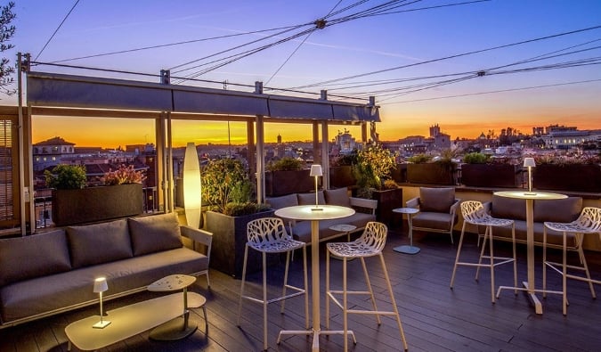 Bar e lounge na cobertura com paisagem urbana ao fundo logo após o pôr do sol no Monti Palace Hotel em Roma, Itália