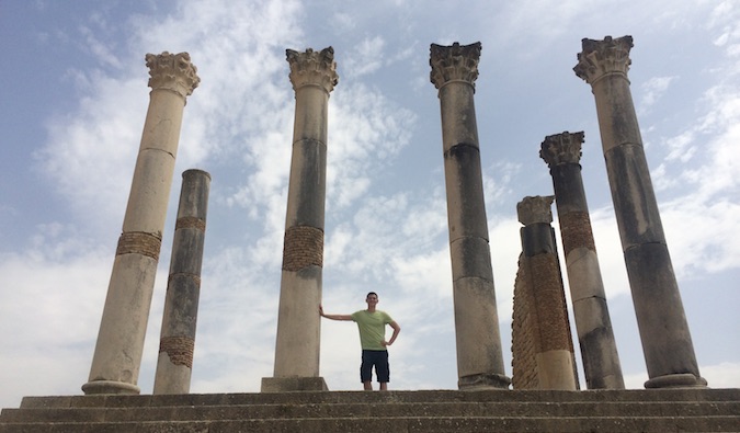 O Nomad Matt posa, admirando as ruínas romanas de Volubilis no Marrocos