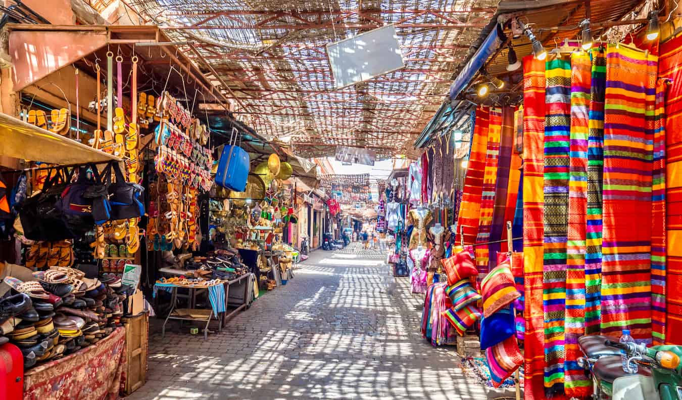 Um beco estreito num mercado tranquilo em Marrocos, repleto de pequenas lojas que vendem produtos coloridos.