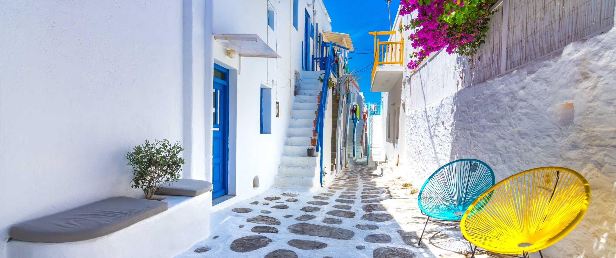 Rua na cidade velha de Mykonos com edifícios brancos como a neve com portas e janelas azuis na ilha de Mykonos, na Grécia.