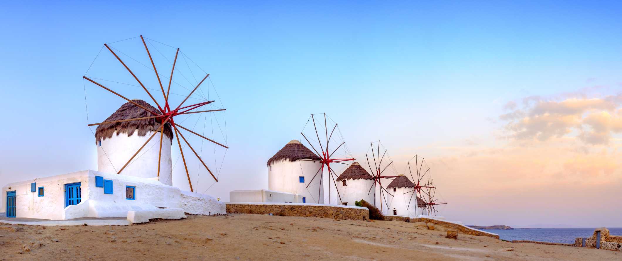 Quatro moinhos de vento ao pôr do sol na ilha de Mykonos, na Grécia