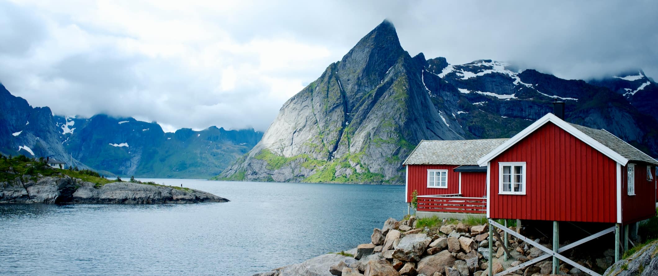 Pitorescos fiordes na Noruega com uma casa vermelha em primeiro plano ao longo da costa cortada