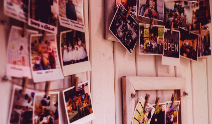 Um monte de fotos antigas penduradas em uma parede de madeira.