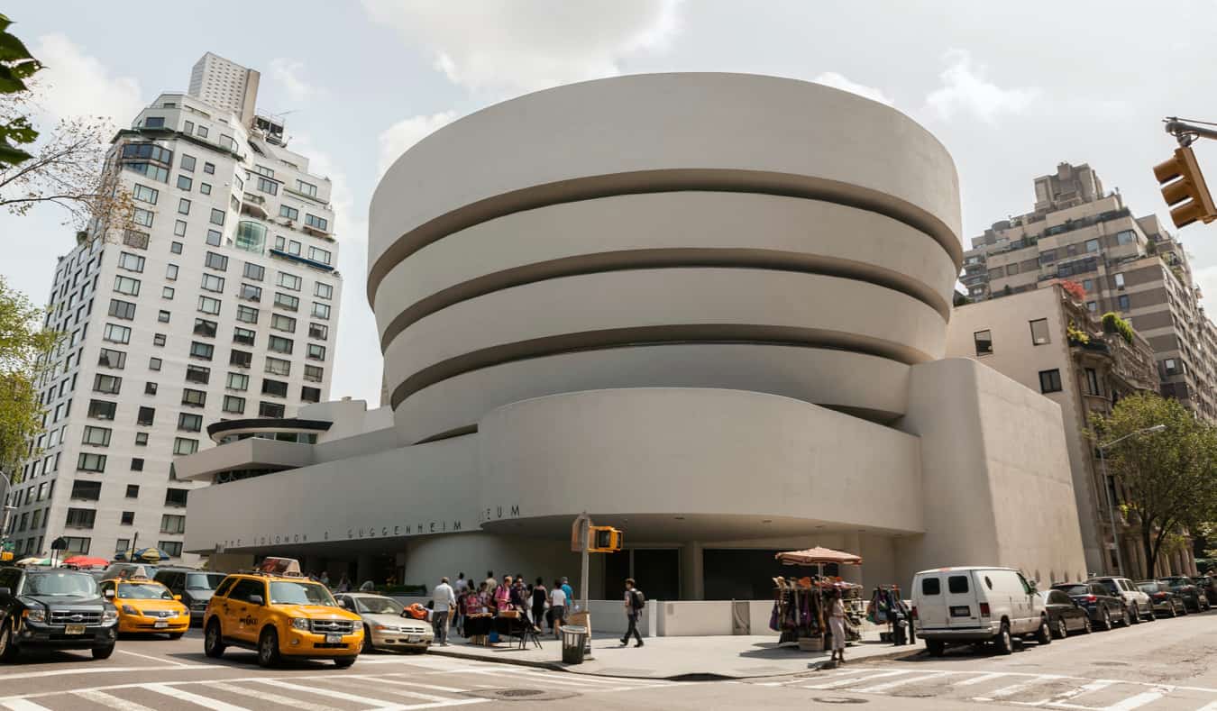 O exterior redondo moderno do Museu Guggenheim, passando por um táxi em Nova York.