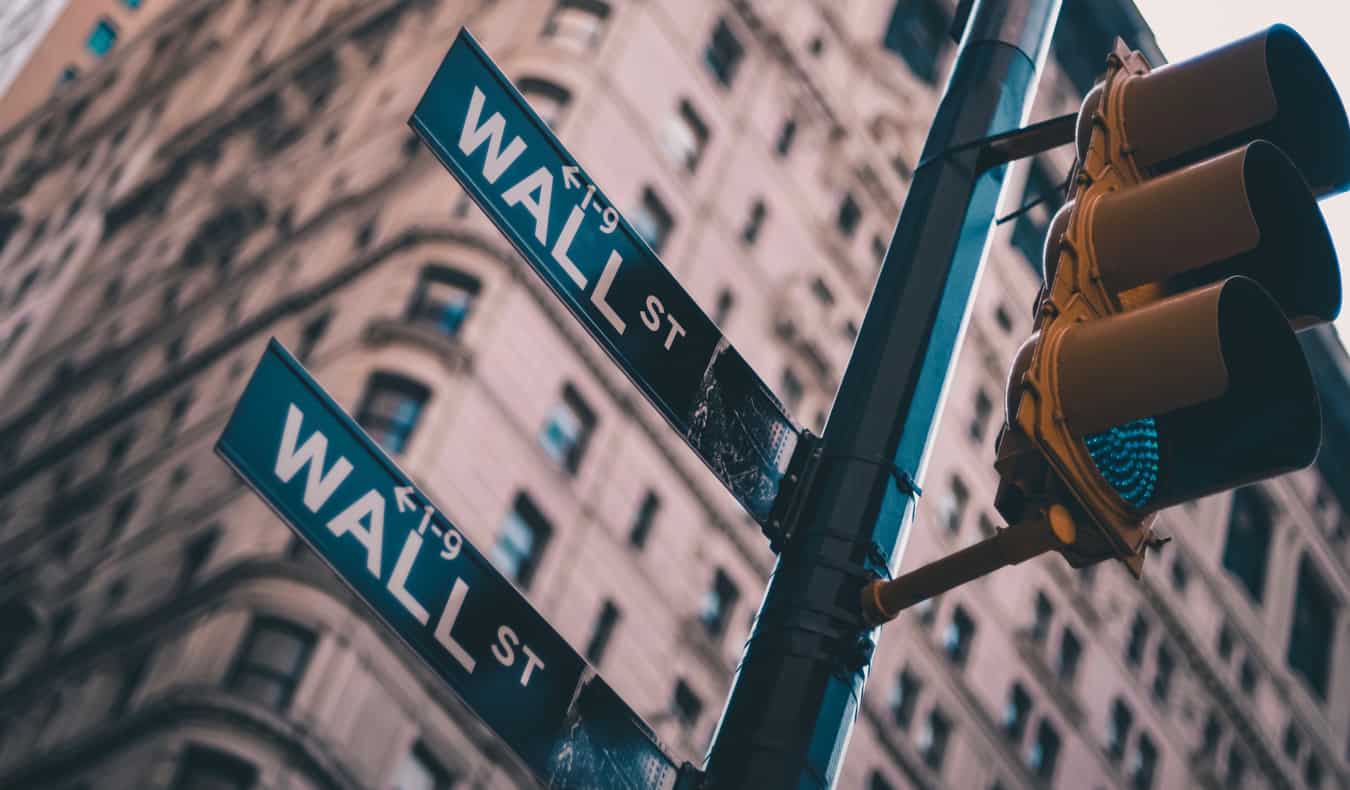 Semáforos de close-up e uma placa de rua em Wall Street