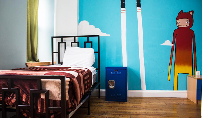 Uma cama de solteiro em um quarto com um afresco pintado na parede no albergue de NY Moore, em Nova York.