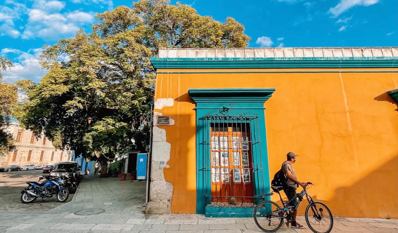 Um morador local em Ohakak, no México, com uma bicicleta perto de um edifício colorido