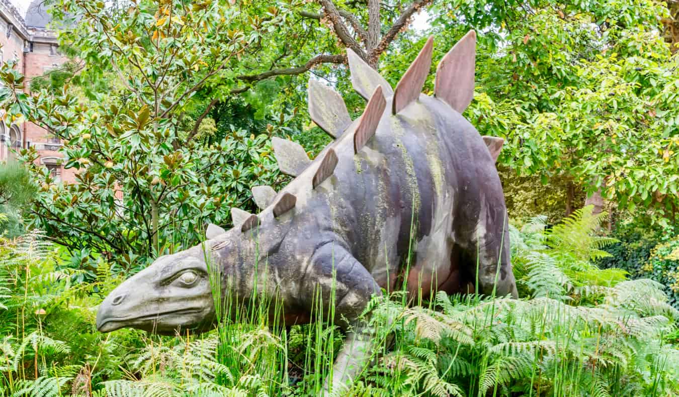 Estátua de um dinossauro em grama alta em Paris, França
