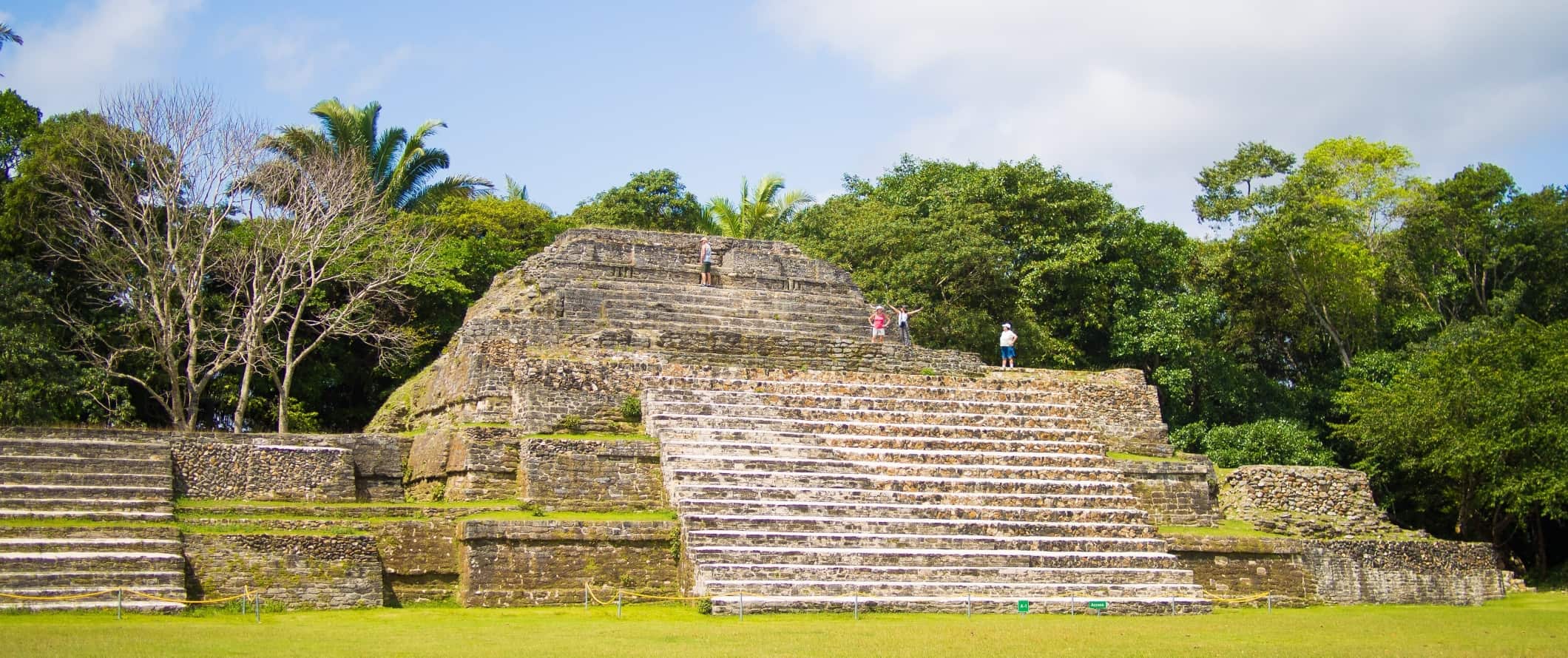 As pessoas andam no topo das pirâmides mult i-tournas da ruína maia, Altun Ha, em Belize