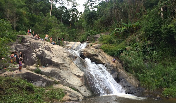 Os mochileiros examinam uma das muitas cachoeiras nas proximidades de Pai, Tailândia