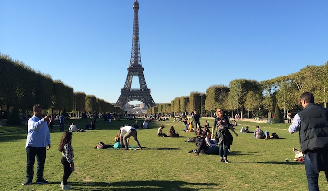 Turistas e moradores locais estão descansando na grama perto da Torre Eiffel em Paris