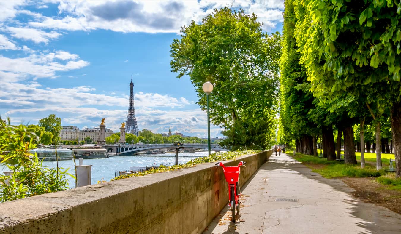 Bicicleta vermelha ao lado do rio em Paris, França, com a torre Eiffel à distância