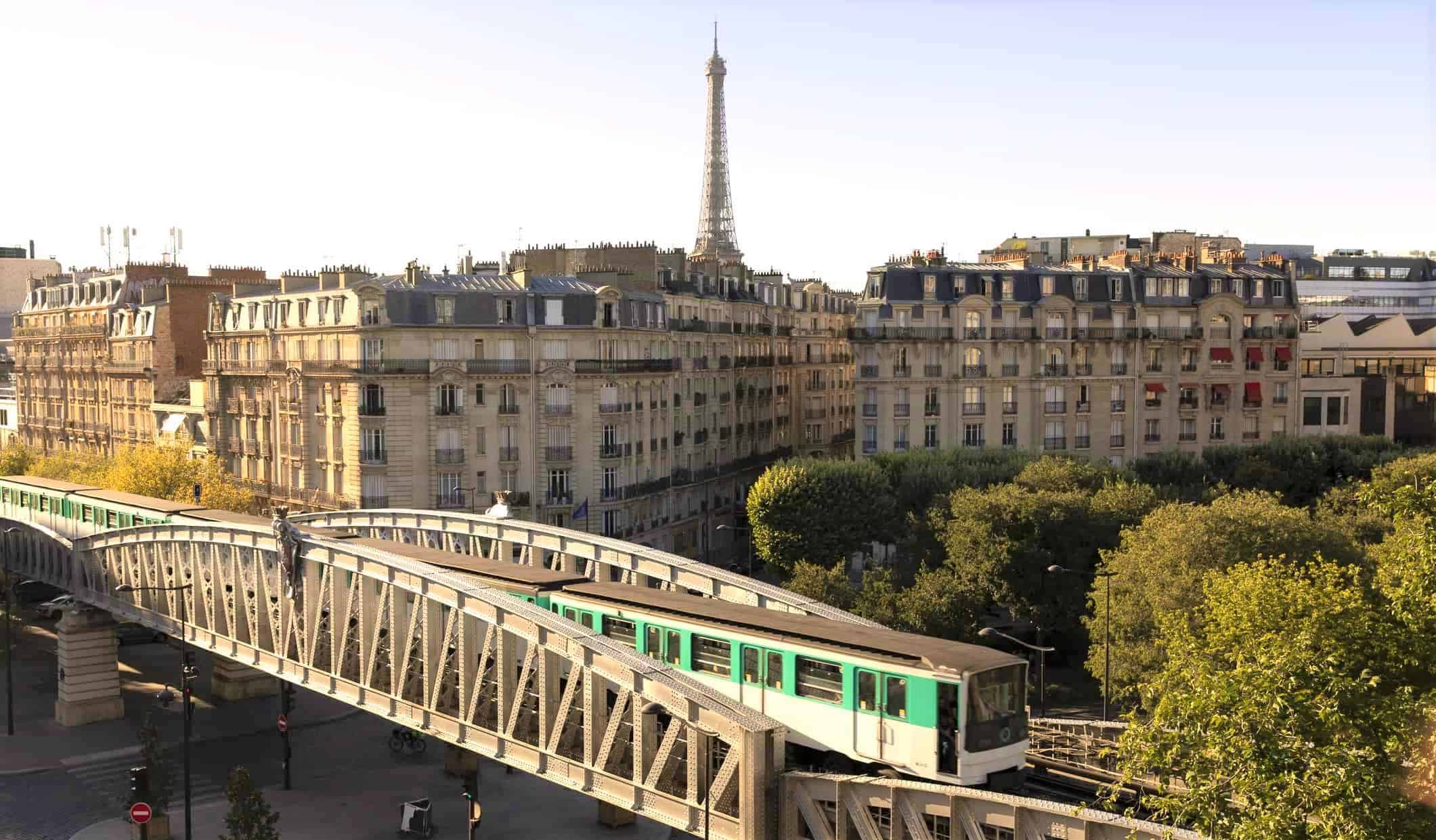 O trem atravessa a ponte em primeiro plano com a Torre Eiffel ao fundo em Paris, França