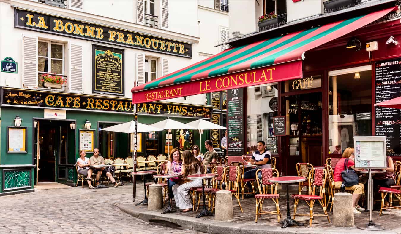 As pessoas gostam dos cafés franceses clássicos no lindo Montmartre em Paris, França