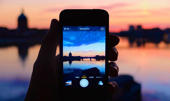 Foto do pôr do sol em um smartphone tirado no exterior, com cores brilhantes à distância