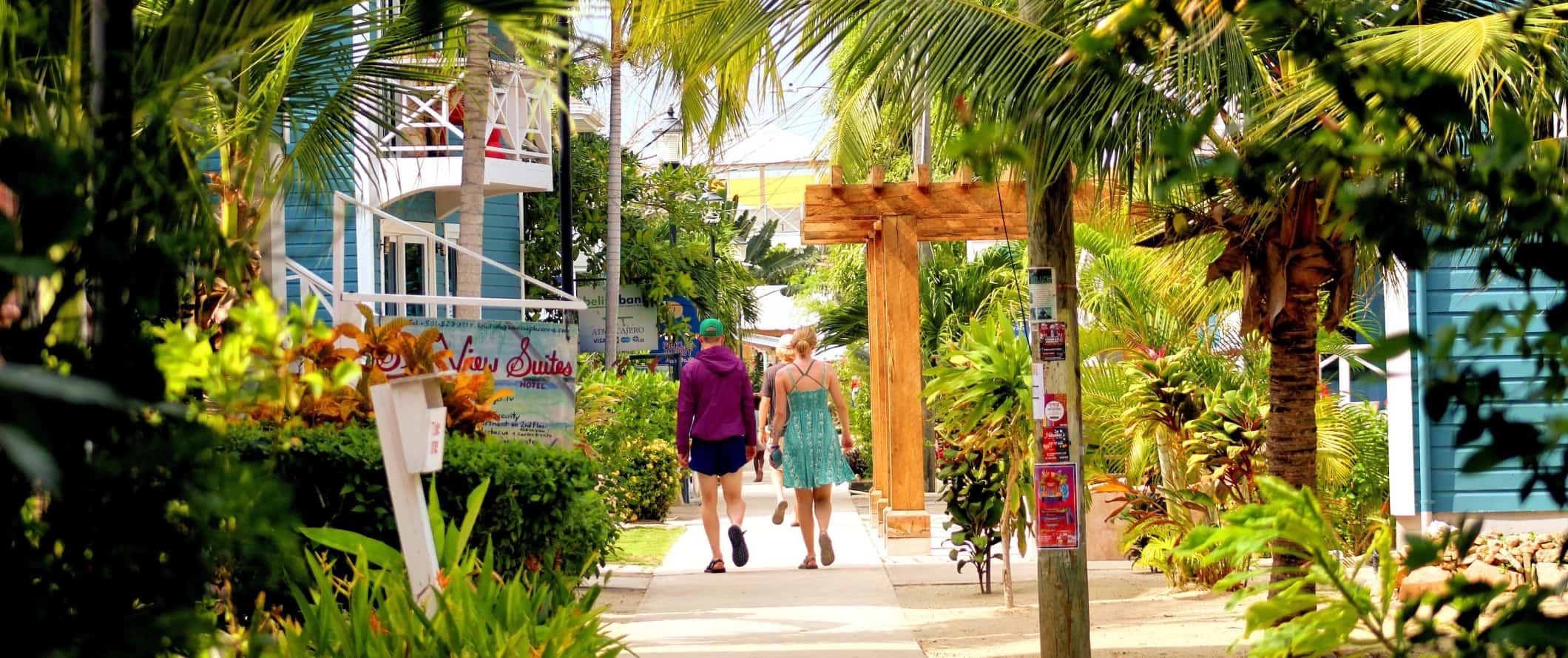 Os turistas vão ao longo da calçada sentados com palmeiras exuberantes, em Platensia, Belize