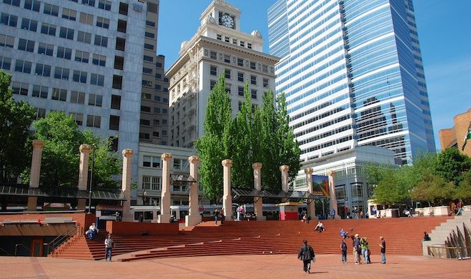 Praça pública ensolarada em Portland, Oregon, com pessoas andando