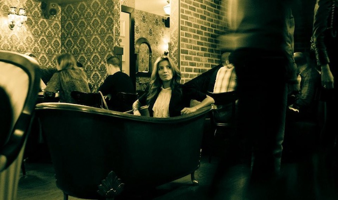 Uma garota sentada em um banho é um destaque do popular estabelecimento de bebida em Nova York, que recebeu o nome apropriado da banheira