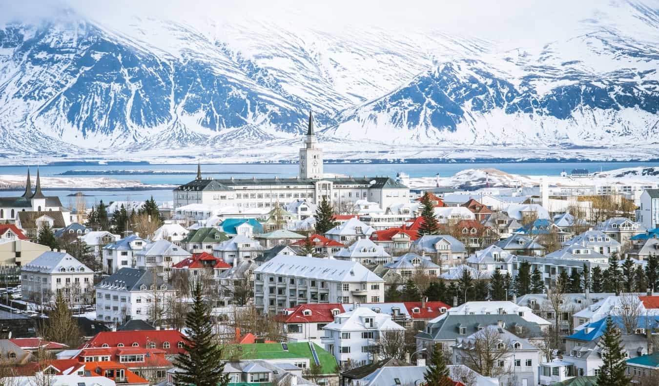 Reykjavik Horizon com telhados com várias coloridos, pináculo da igreja e montanhas com pancadas de neve ao fundo da Islândia na Islândia