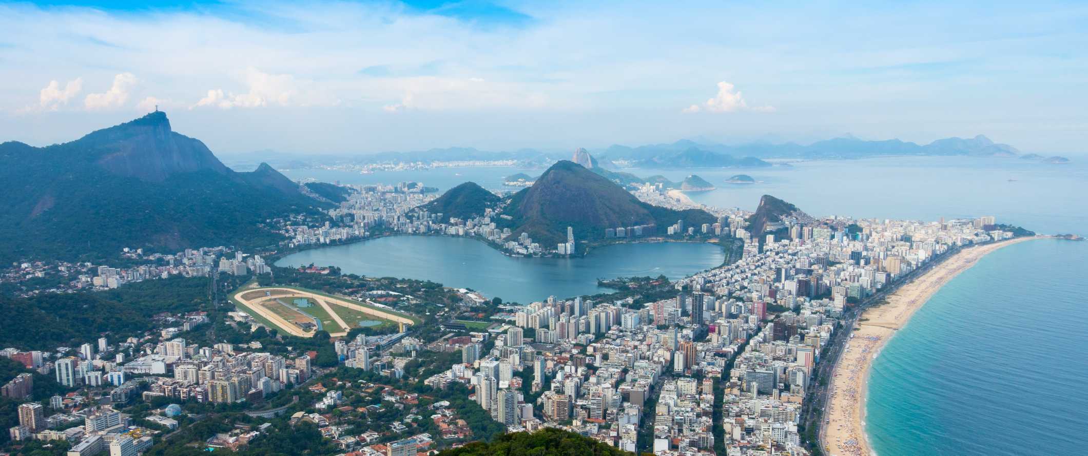 Vista panorâmica do Rio de Janeiro com arranha-céus ao longo da praia e montanhas ao fundo