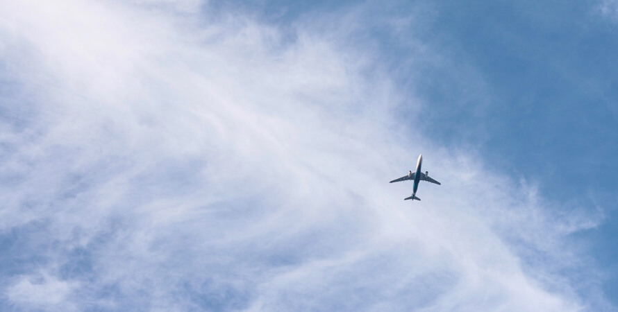 Um avião comercial solitário voando contra um céu azul brilhante.