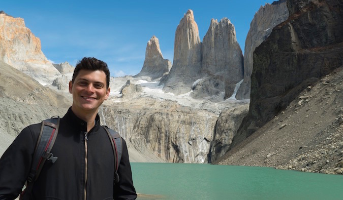 Nomad Matt posa para uma foto em Torres del Paine com montanhas imponentes ao fundo