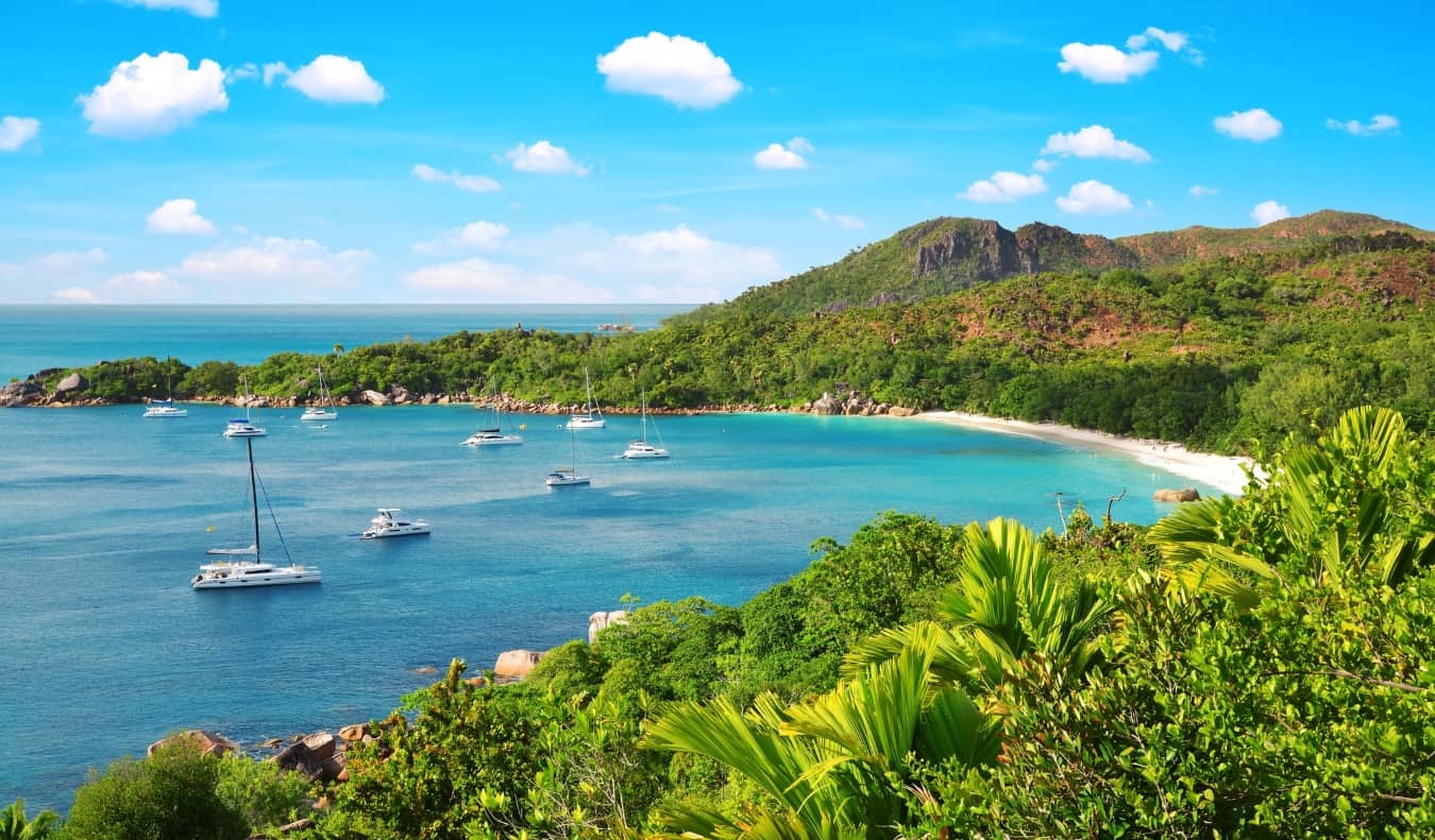 Barcos à vela em uma baía calma cercada por colinas exuberantes nas Seychelles