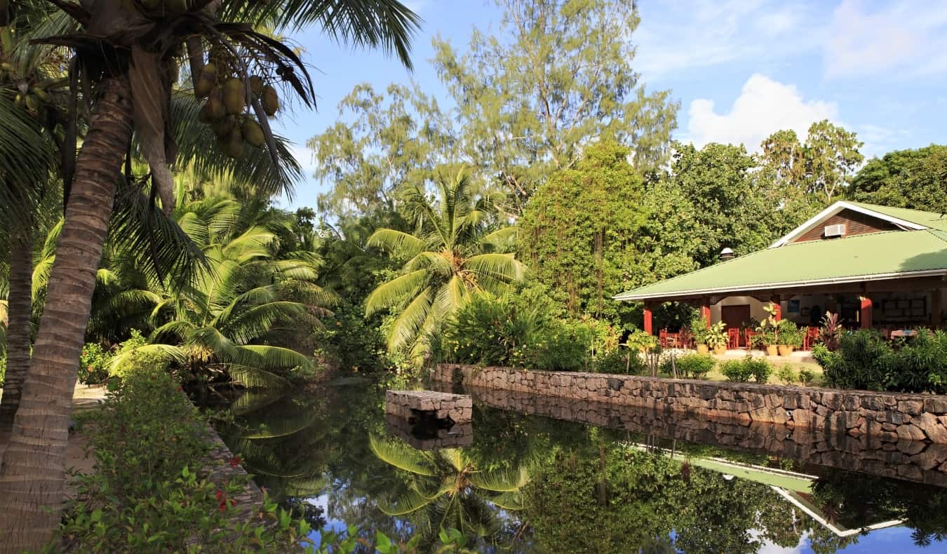 House House com vista para um canal calmo, cercado por uma densa floresta de palmeiras nas Ilhas Seychelles